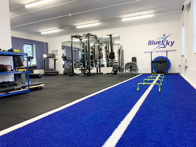 A wide view of the gym at Blue Sky Physiotherapy. There are free weight, weight machines and a short track area.